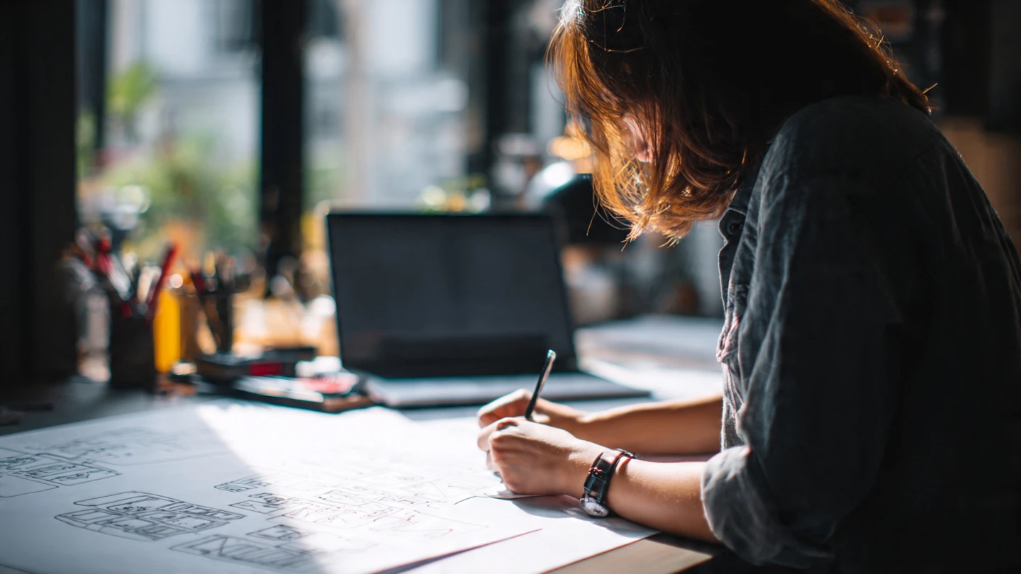 Creative process of website and experience design in El Salvador, designer sketching digital interface concepts, natural workspace, GrafoWeb agency